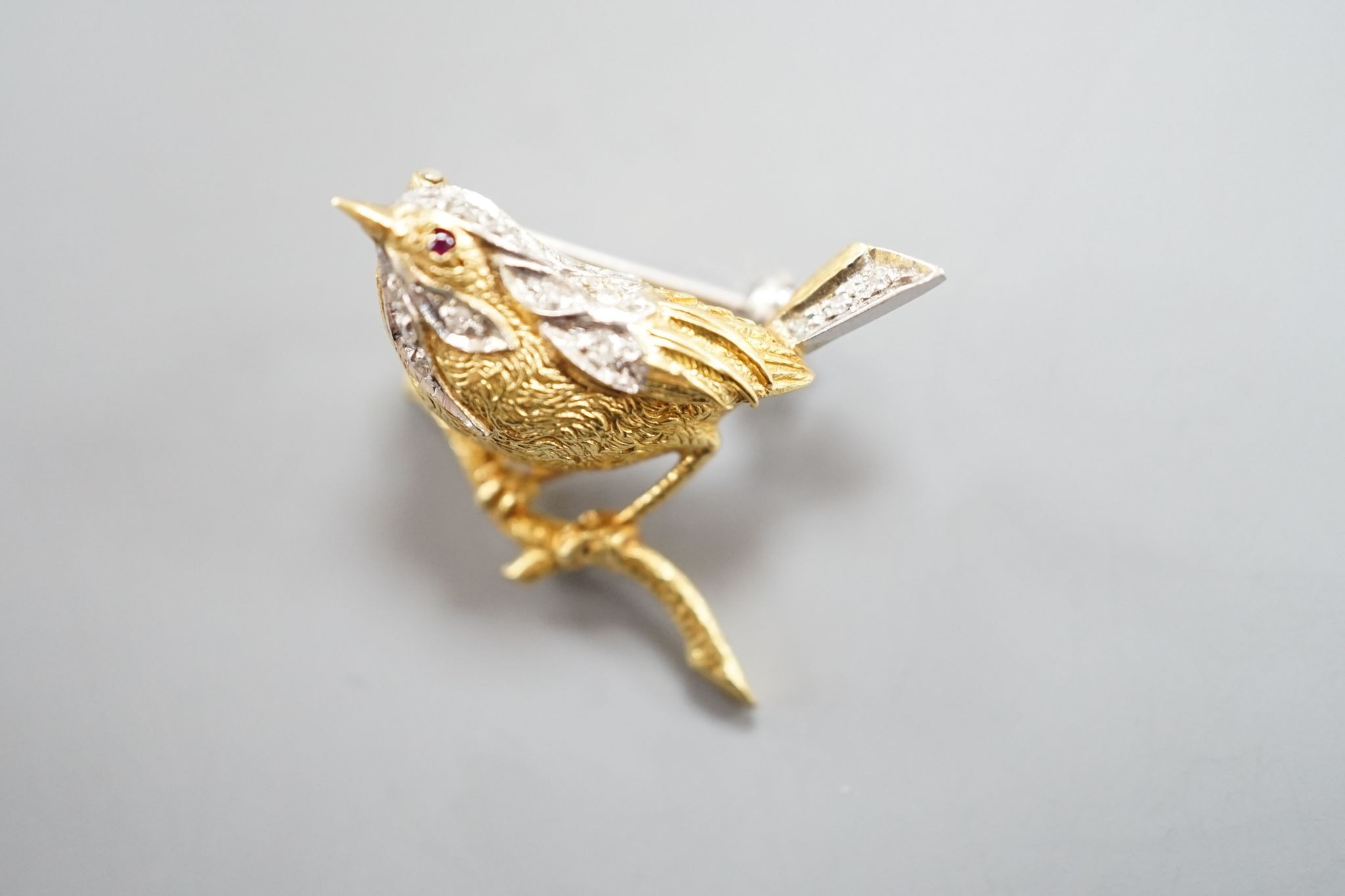 A modern textured 18ct two colour gold, ruby and diamond set bird brooch, 24mm, gross weight 6 grams.